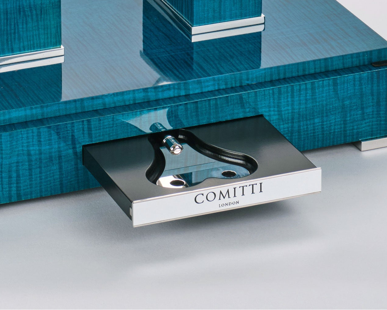 Close-up of a blue maple base with 'Comitti London' branding on a key tray
